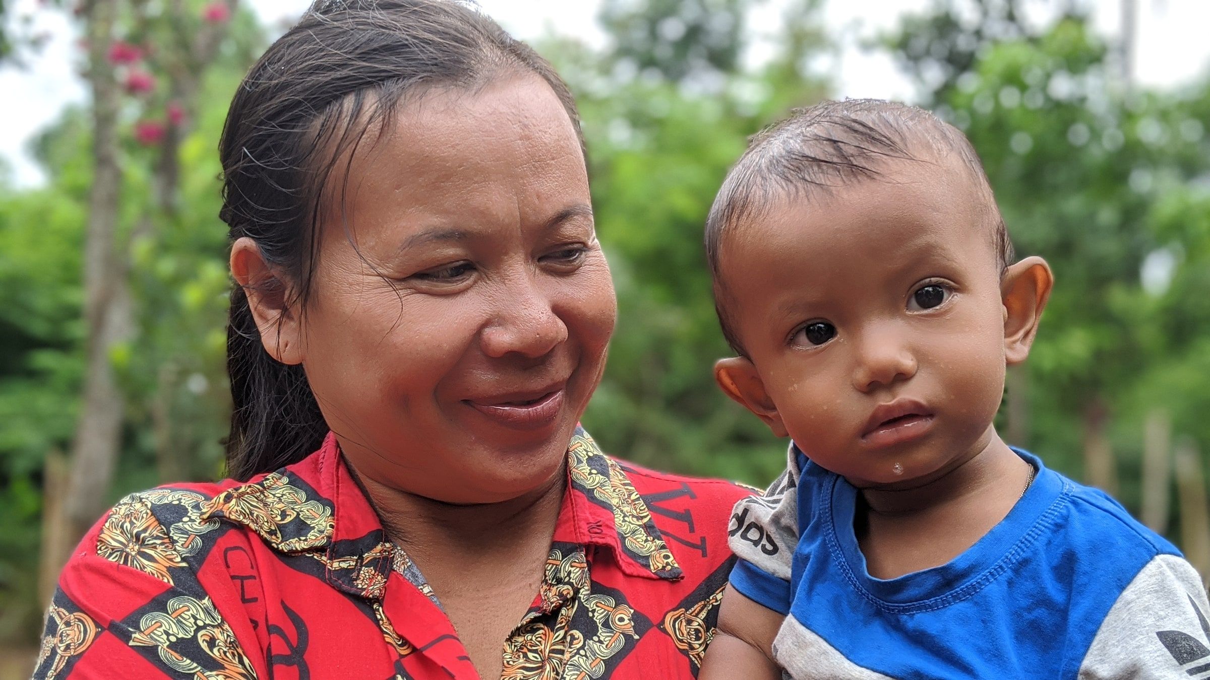 A mother holding her baby, both looking at the camera